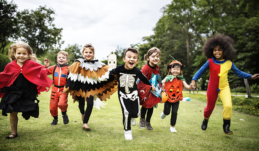 Kids in Halloween disguises run. 