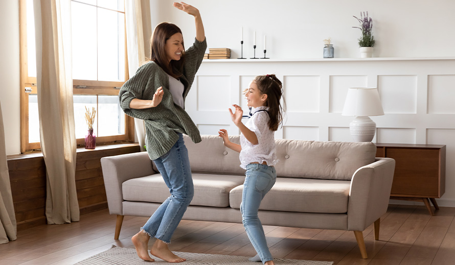 A mother and daughter dance inside to keep active.