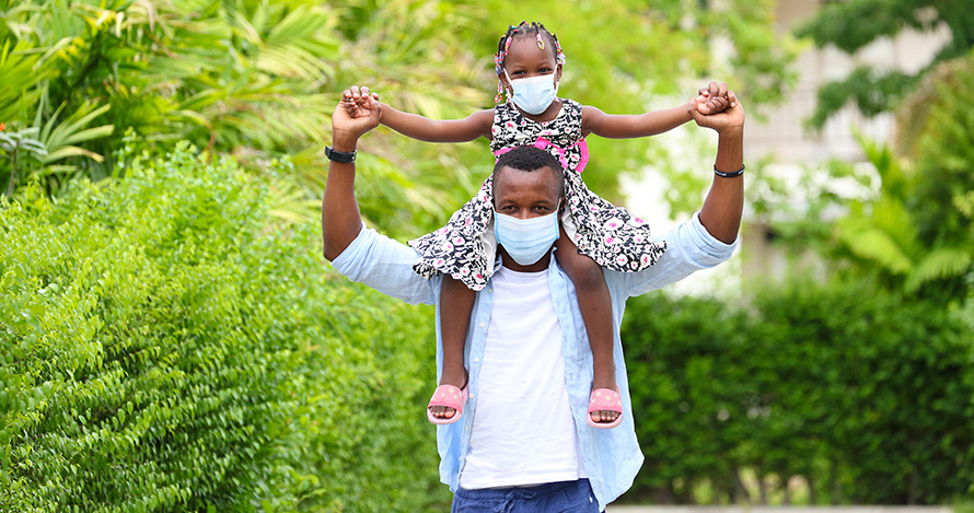 An African American child sits atop her father's shoulders.