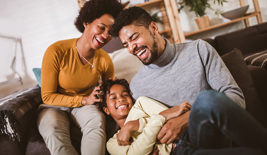 African-American father and mother tickle daughter at home. 