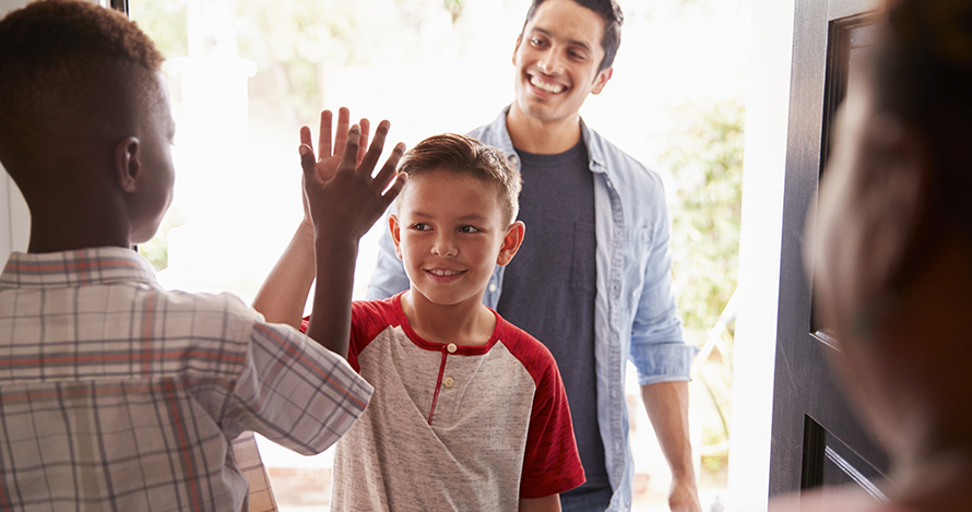 An African American boy welcomes his Hispanic friend over for a playdate. 