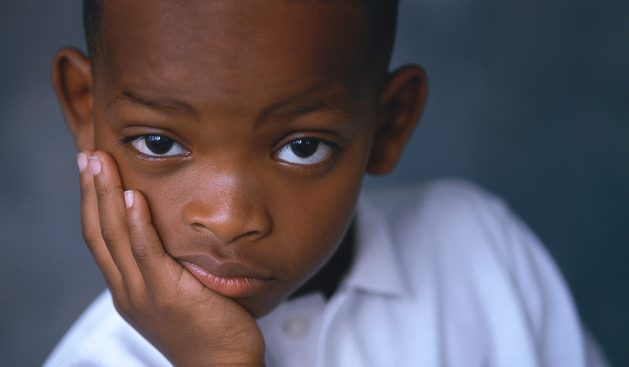 Young boy with his chin in his hand, sporting a dubious look on his face